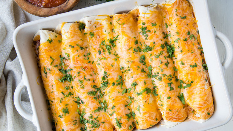 Enchiladas in baking dish, topped with melted cheese and chopped cilantro