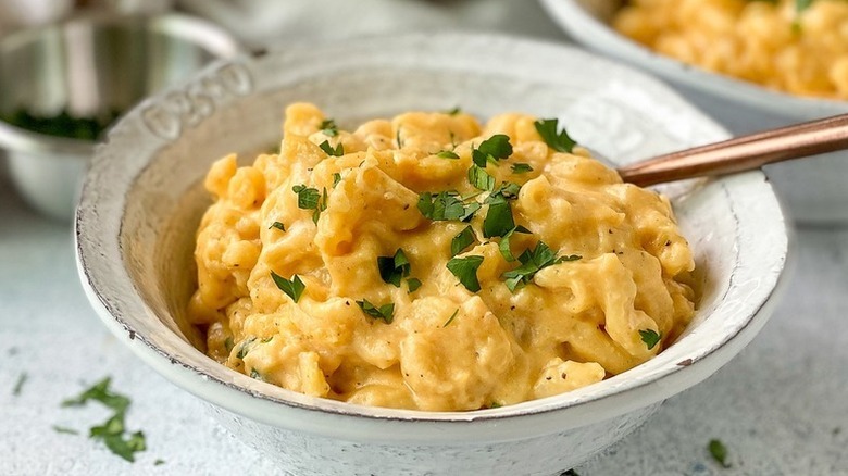 Bowl of mac and cheese topped with chopped parsley