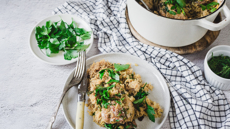 Portion of one-pot chicken and rice on plate with fresh parsley garnish