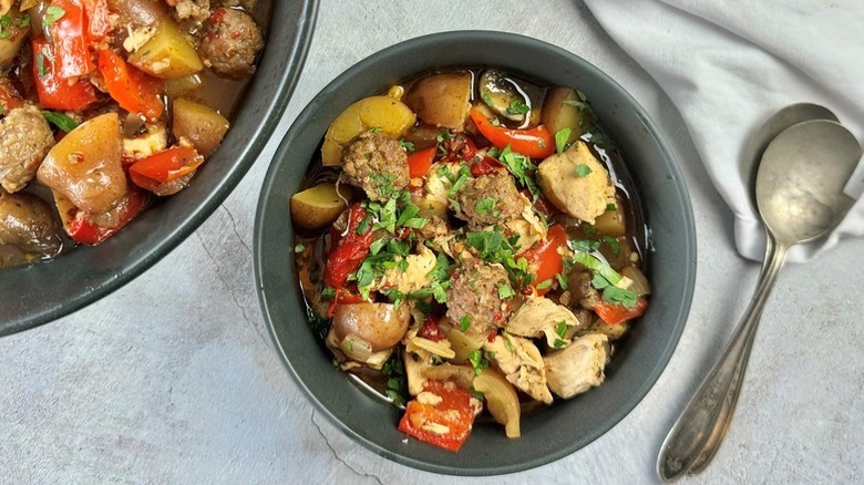 Bowl of chicken, potato, and vegetable stew next to two spoons