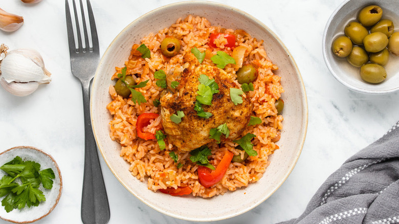 Bowl of spicy chicken and rice with olives and red peppers