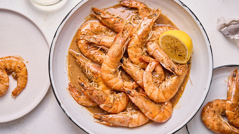 Saucy whole fried shrimp in bowl with lemon half