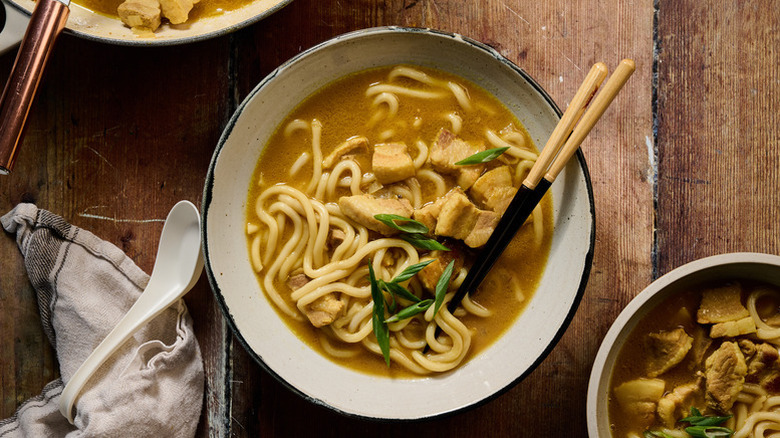 Bowl of chicken udon noodle curry with chopsticks