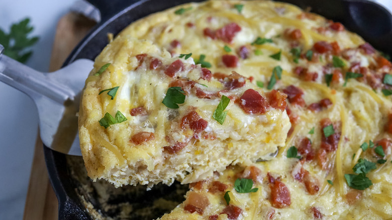 Slice of spaghetti carbonara frittata being lifted from skillet