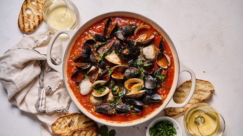 Steamed mussels and clams in casserole pot with tomato sauce