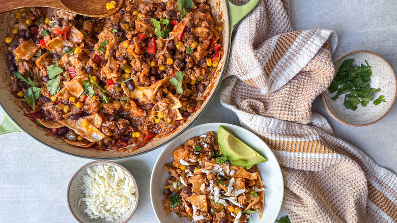 Turkey enchilada skillet served into bowl with shredded cheese, herbs, and avocado