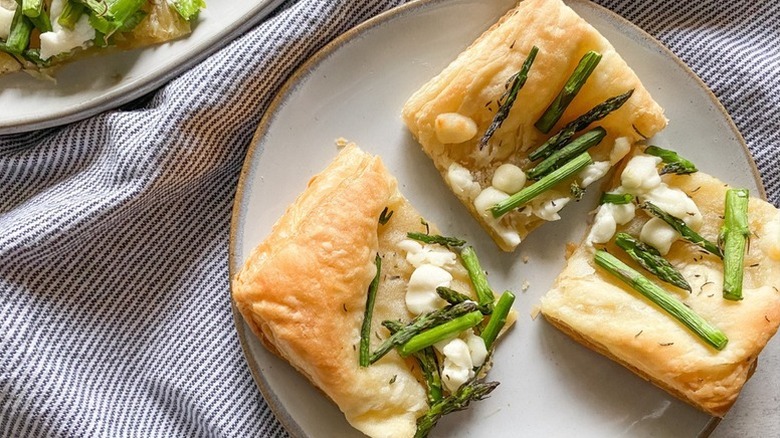 Three squares of asparagus and goat cheese puff pastry tart on plate