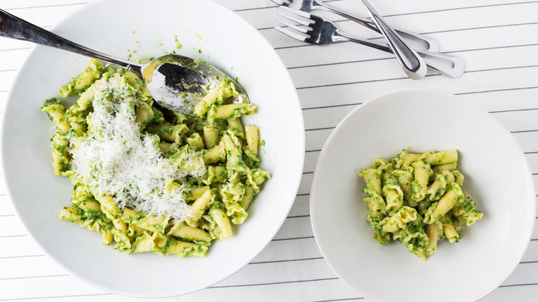 Bowls of pesto pasta with grated Pecorino cheese on top
