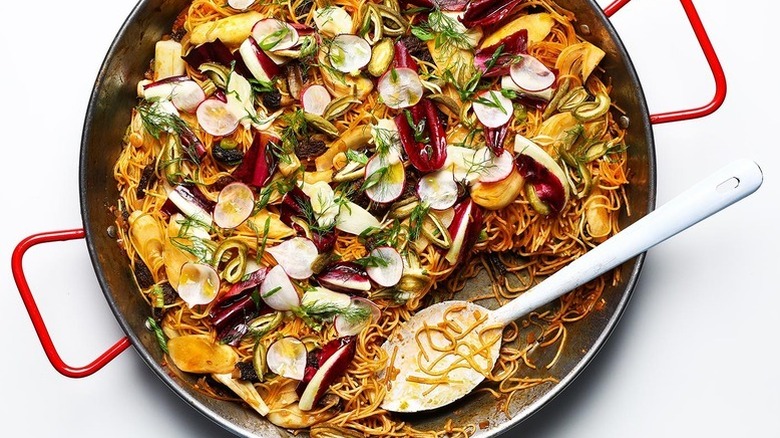 Top view of spring vegetable fideos in paella pan with a spoon