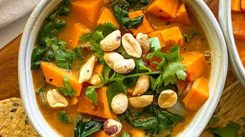 Hearty Peanut Butter Soup in white bowl with peanuts on top