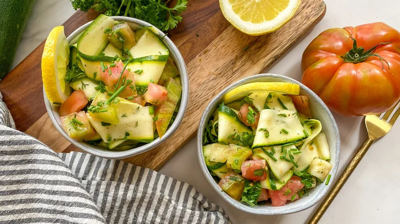 Herby Zucchini Ribbon Salad in grey bowls on wooden board