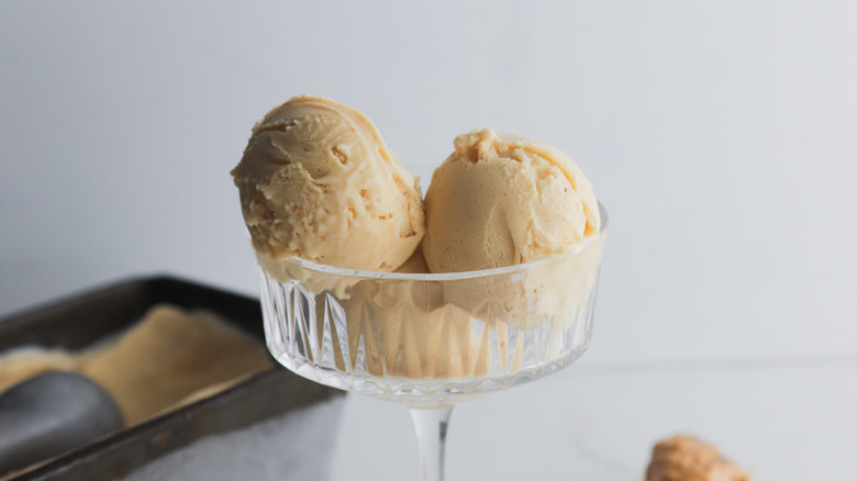 Three scoops of peanut butter ice cream in glass dessert bowl