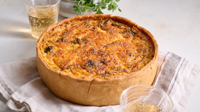 Golden brown baked quiche on grey linen