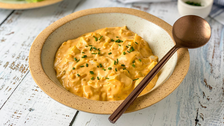 Bowl of deviled egg salad, garnished with chopped chives