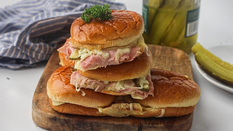 Pile of ham and cheese sliders on wooden board