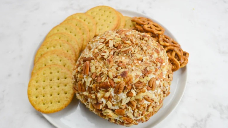 Cheese ball on a plate with snack crackers and pretzels