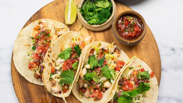 Cilantro Lime Shrimp Tacos on wooden board with salsa and cilantro