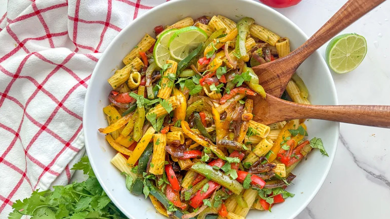 Fajita Pasta with Cilantro Lime Sauce in large white bowl with wooden spoons