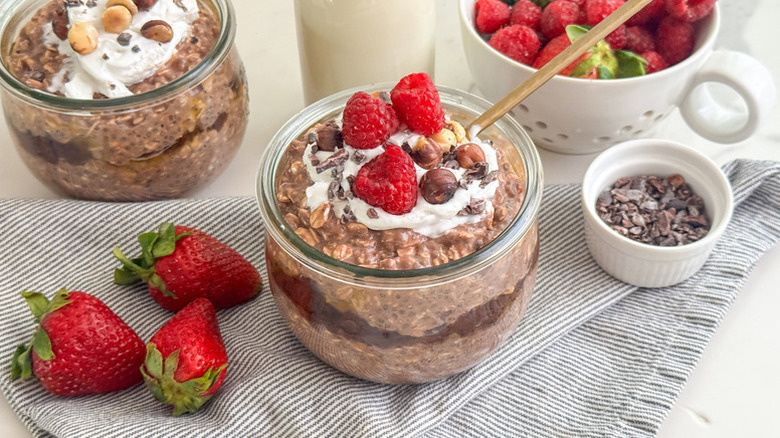Chocolate overnight oats in dessert glasses, topped with fresh raspberries