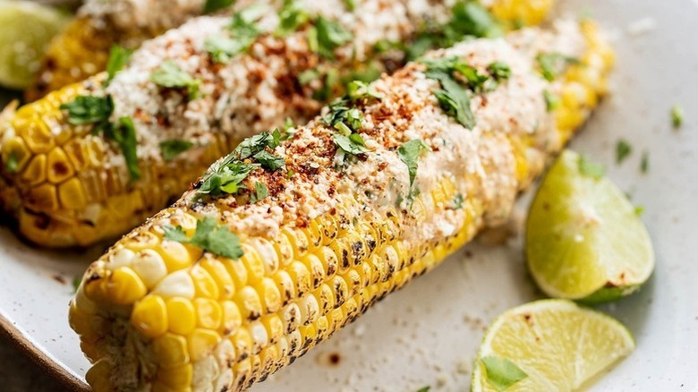 Grilled Mexican street corn topped crema crema, Tajín, and chopped cilantro