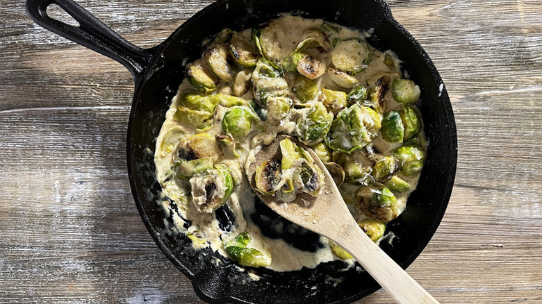 Creamed Brussels sprouts in skillet with wooden spoon