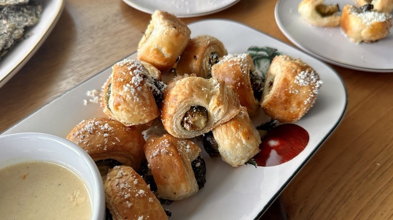 Pastry-wrapped Brussels sprouts on serving plate with bowl of creamy dip