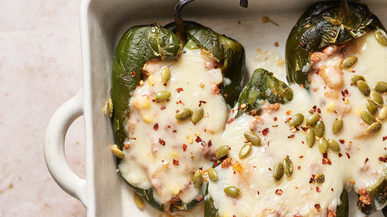 Cheesy roasted poblano peppers in baking dish, sprinkled with pepitas