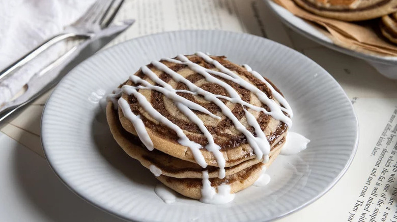 Cinnamon Roll Pancake on white plate with drizzled glaze