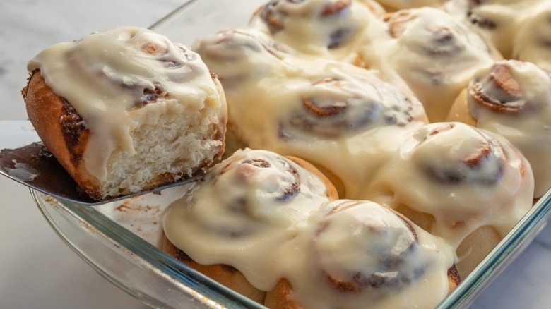 Easy Cinnamon Roll being lifted out of glass baking dish