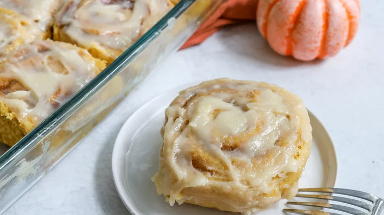 Fall-Worthy Pumpkin Cinnamon Rolls with Cream Cheese Frosting on white plate