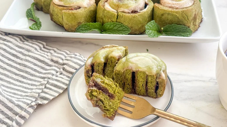Matcha Cinnamon Rolls with Cream Cheese Frosting on white plate with fork