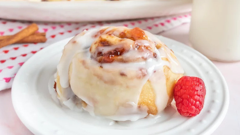 Raspberry Cinnamon Rolls on white plate with raspberry