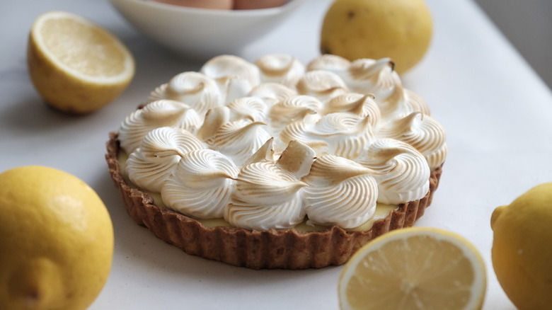 Lemon meringue pie surrounded by fresh lemons