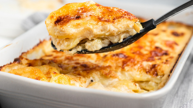 Spooning scalloped potatoes from baking dish