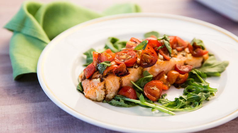 Baked salmon fillet topped with cherry tomatoes and basil.