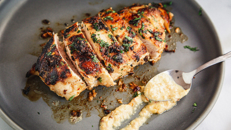 Sliced grilled chicken on plate with honey mustard sauce.