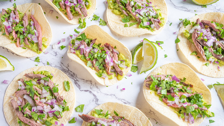 Tacos with tri-tip steak, red onion, cilantro, and guacamole.