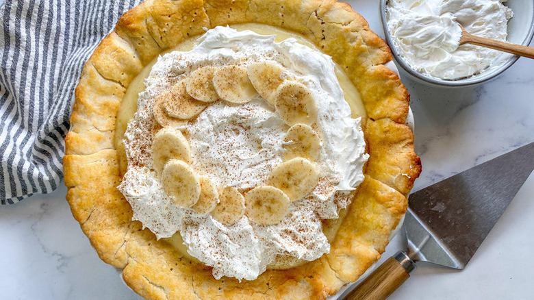 Banana cream pie next to a bowl of whipped cream