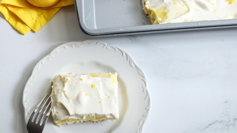 Creamy lemon lush dessert on a plate and in a baking dish