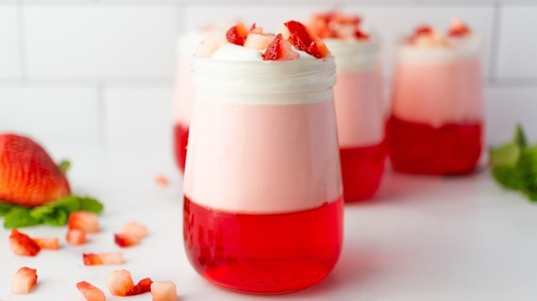 Strawberry Jell-O parfaits in glasses, topped with fresh strawberry pieces