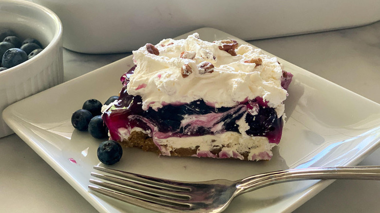 Slice of a creamy layered blueberry dessert on a plate