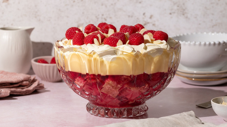 Traditional British trifle in a glass dessert bowl, topped with fresh raspberries and flaked almonds