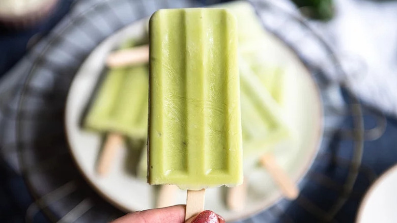 Avocado Ice Pop being held in front of plate of pops
