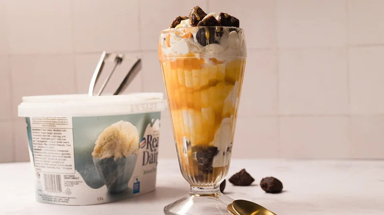 Copycat Costco Caramel Brownie Sundae next to tub of vanilla ice cream
