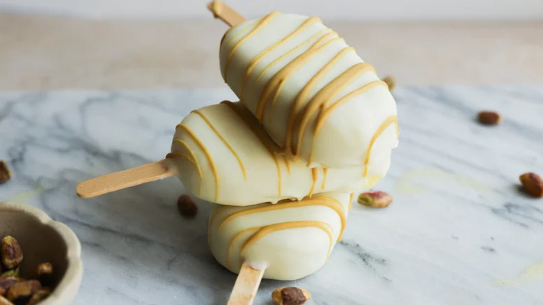 Decadent White Chocolate Pistachio Ice Pops stacked on granite countertop
