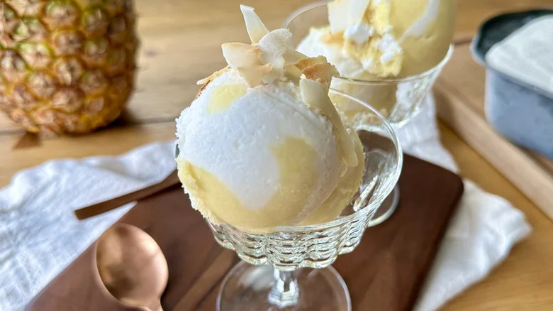 No-Churn Swirled Piña Colada Sorbet in glass goblet on wooden board