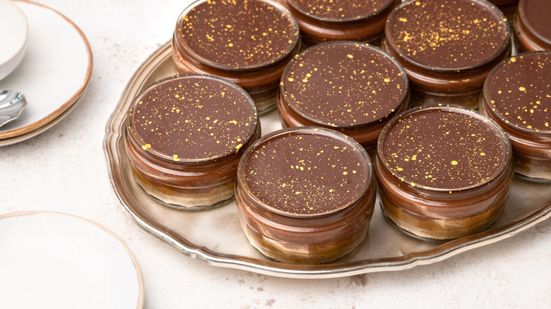 Chocolate and salted caramel cheesecake pots assembled on metal serving platter