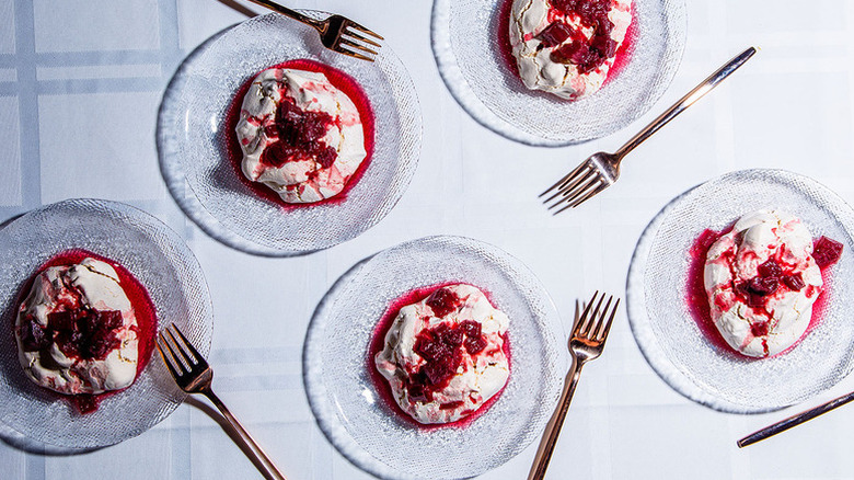 Top view of hazelnut meringue cookies on plates, each topped with rhubarb and red wine conserva