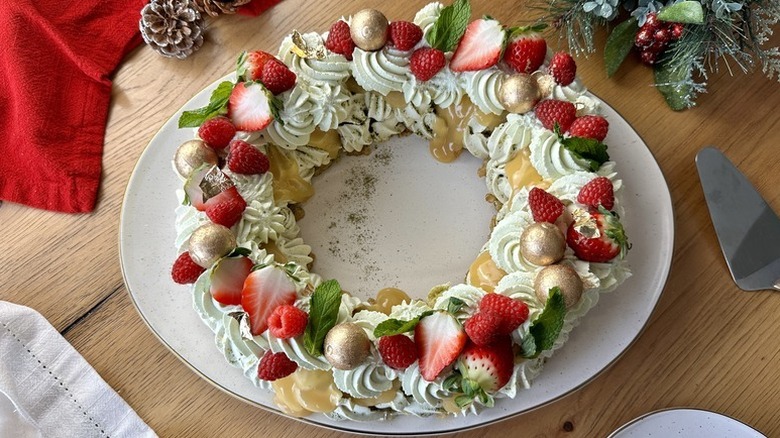 Matcha pavlova Christmas-inspired wreath on plate, garnished with chocolate pralines, mint, strawberries, and raspberries