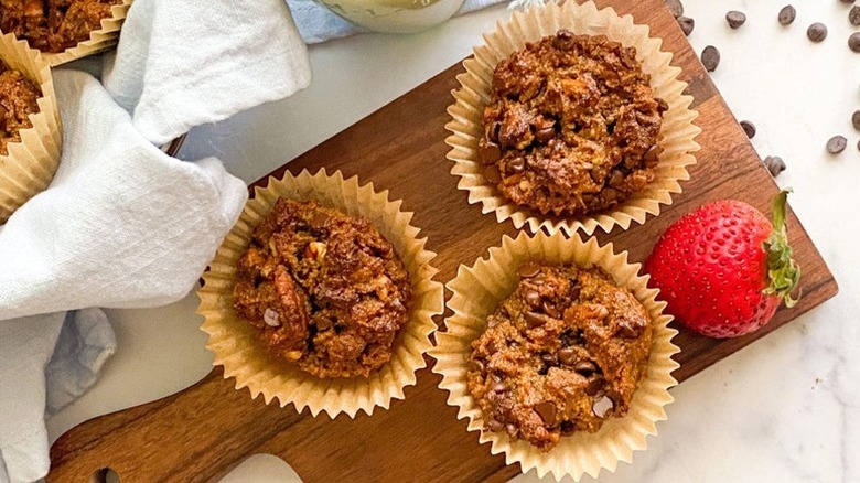 Pecan pie muffins in paper muffin cases on wooden board with a strawberry on the side